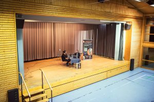 Live-Podcast Adrian lädt ein... mit Buchpräsentation Silvia Kolb, Trotzdem...glücklich...erfolgreich...alles!, am 16. Oktober 2025 in Offenburg in der Freihofhalle Waltersweier. Bühnenansicht mit Adrian Hoffmann und Silvia Kolb.