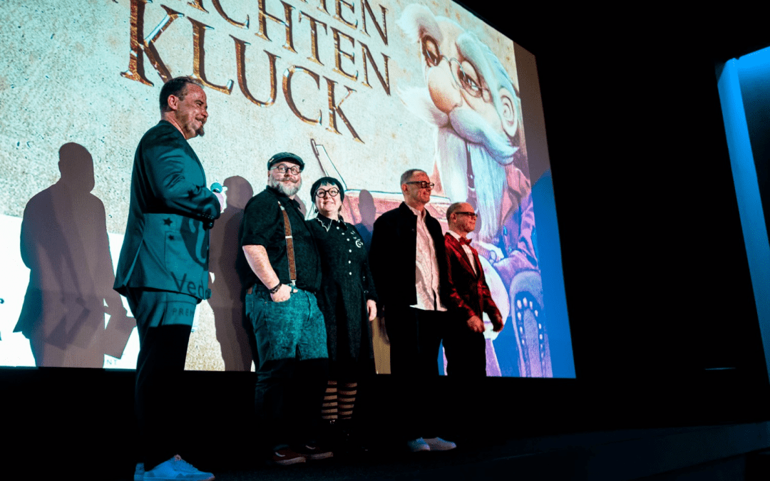 Moderations im Scala Kino mit Blick auf die Bühne vor der Leinwand mit dem Hauptmotiv des Films und den vier Haupt-Initiatoren Norman und Alexander Schneider von Figurenschneider und Christian Confer und Jana von Kluck Kola_Moderation Warendorf_Premiereabend_Die fantastischen Geschichten des Professor Kluck